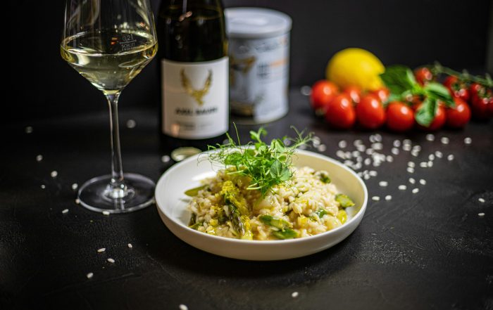 Risotto alla Milanese with saffron, Parmigiano Reggiano and butter on a table with red wine, salt and ingredients