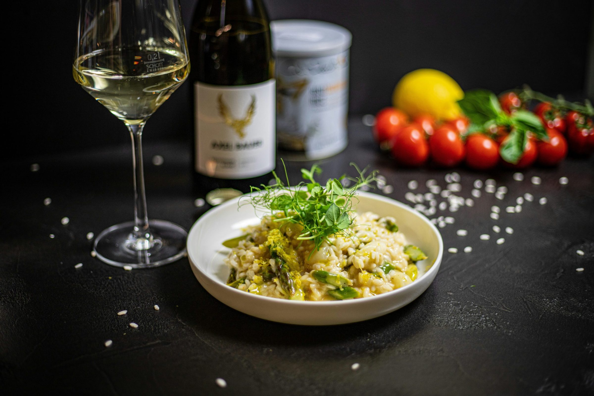 Risotto alla Milanese with saffron, Parmigiano Reggiano and butter on a table with red wine, salt and ingredients